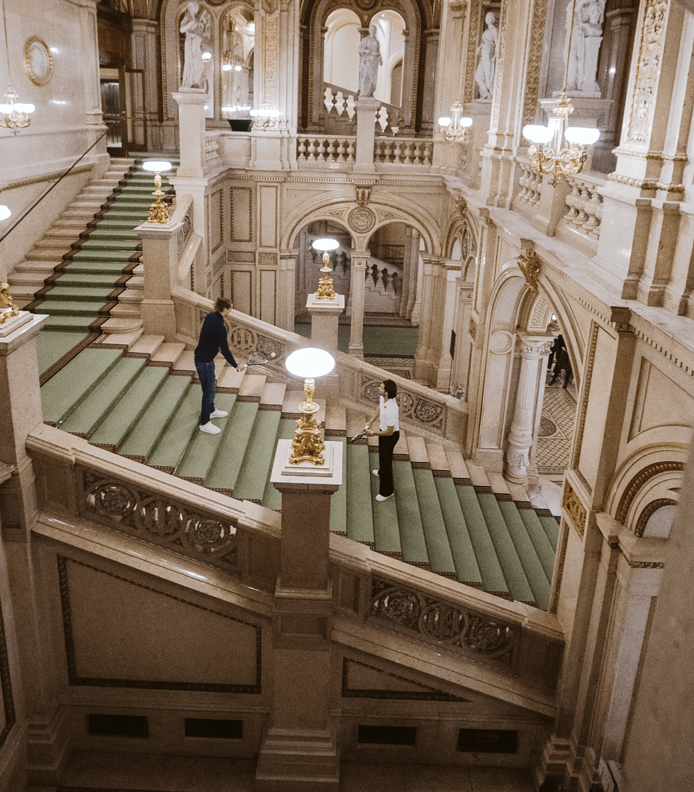 Alexander Zverev and Carlos Alcaraz playing tennis on the grand staircase of the Vienna State Opera